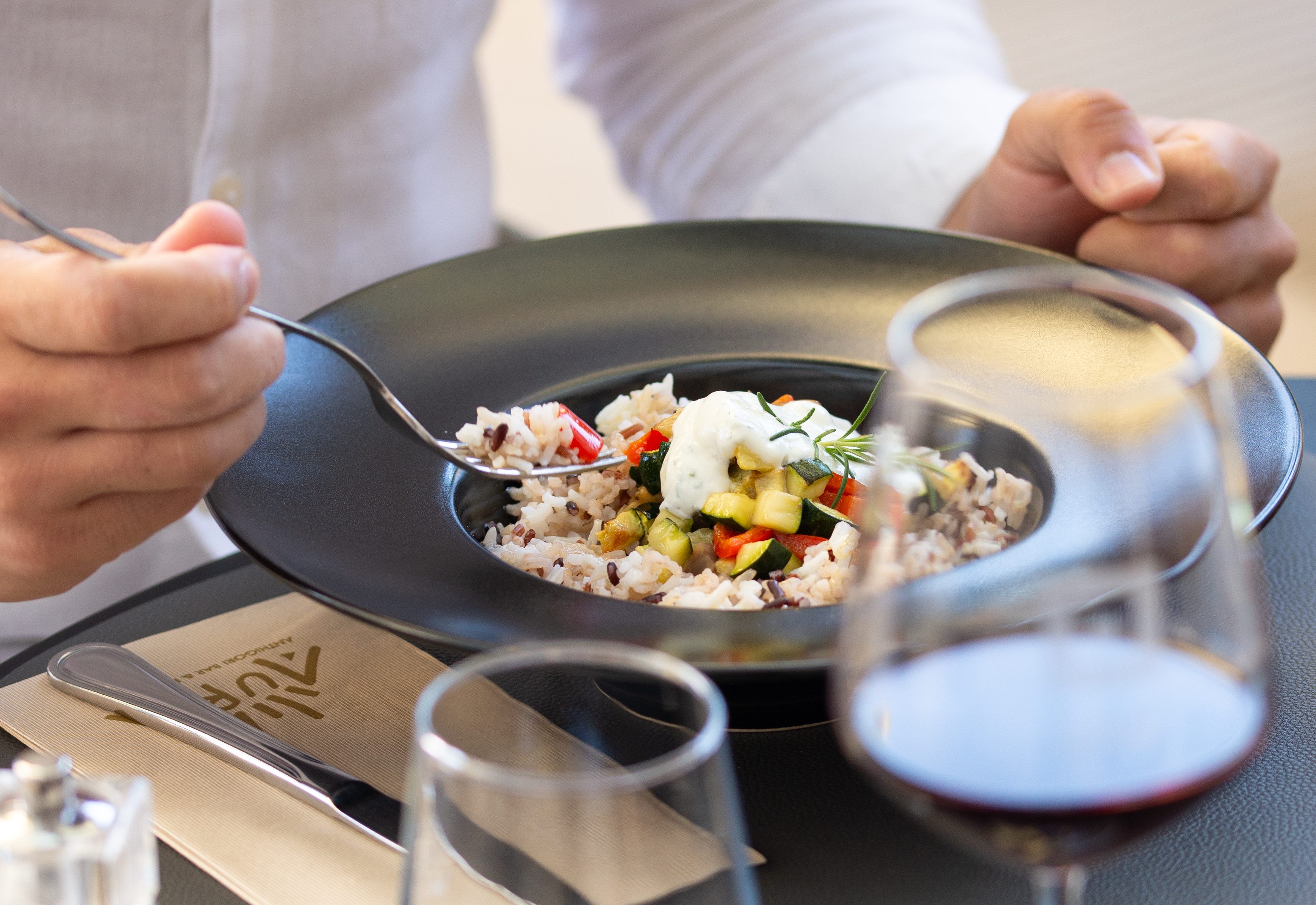 Chef presenting beautifully plated dish with colorful vegetables and burrata